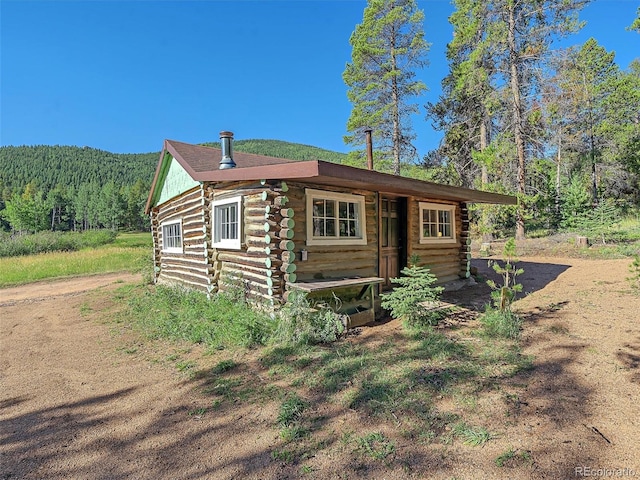 log cabin featuring log siding and a forest view