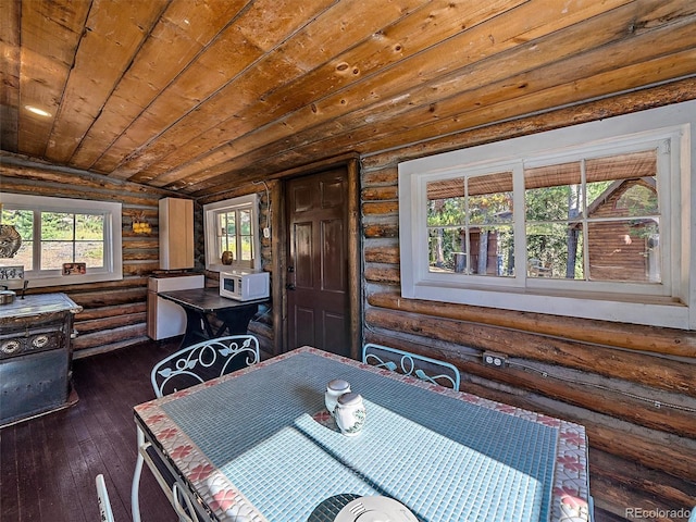 dining area featuring rustic walls and dark wood finished floors