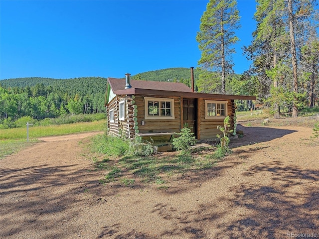 view of outbuilding featuring dirt driveway and a view of trees