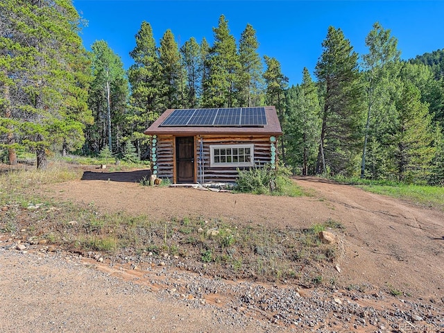 view of outdoor structure featuring a view of trees and solar panels