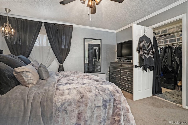 carpeted bedroom with a spacious closet, a textured ceiling, ceiling fan, and ornamental molding