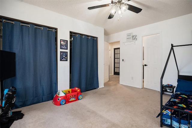 carpeted bedroom with a textured ceiling and a ceiling fan