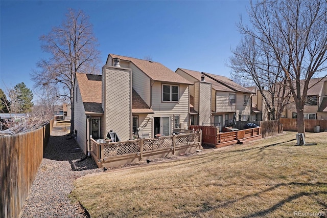 back of property featuring a deck, fence, a lawn, and roof with shingles