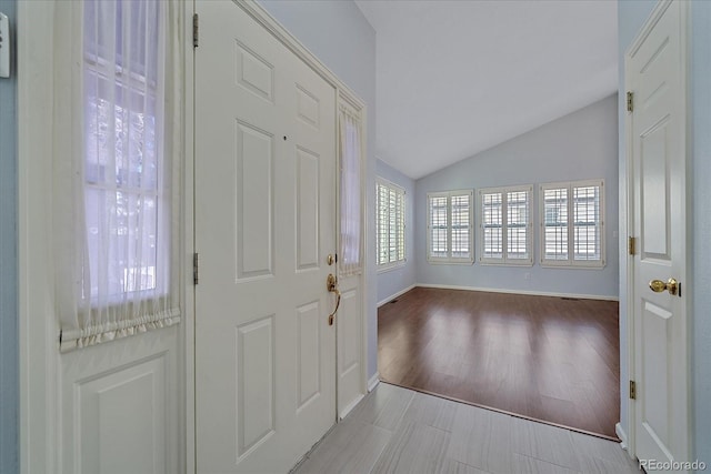 foyer with light hardwood / wood-style floors and vaulted ceiling