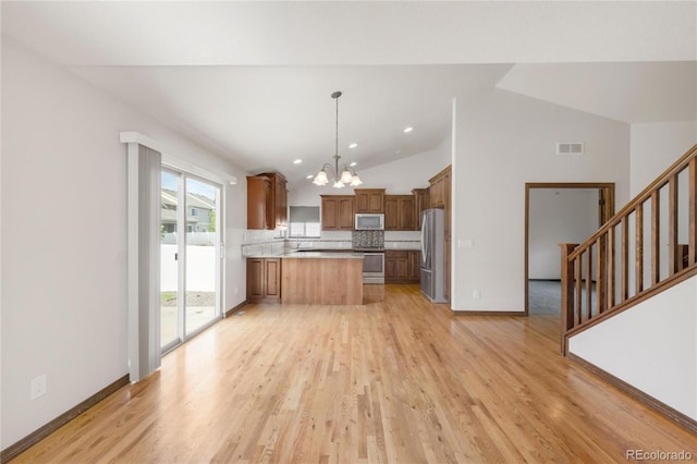 kitchen featuring freestanding refrigerator, a chandelier, range, a peninsula, and light wood-type flooring