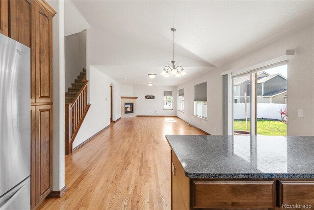 kitchen featuring freestanding refrigerator, vaulted ceiling, light wood-type flooring, a chandelier, and open floor plan