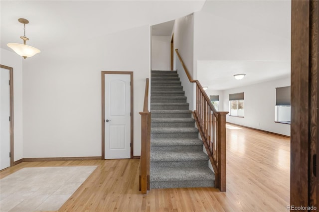 staircase featuring wood finished floors and baseboards