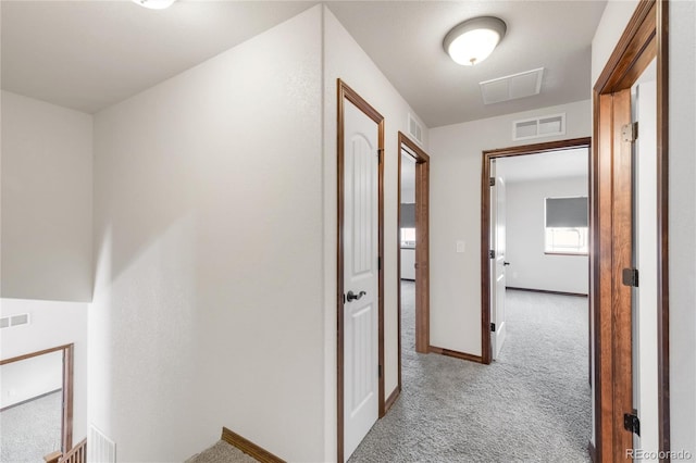 hall with carpet flooring, an upstairs landing, and baseboards