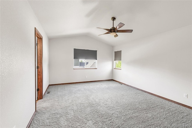 carpeted spare room with a ceiling fan, lofted ceiling, and baseboards