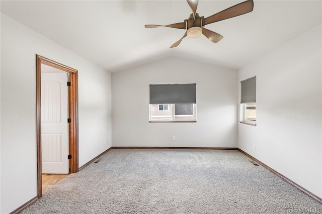 carpeted empty room featuring ceiling fan, vaulted ceiling, and baseboards