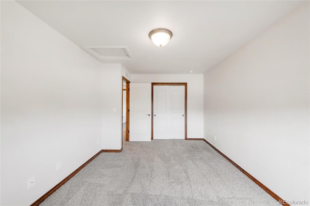 unfurnished bedroom with carpet, attic access, baseboards, and a closet