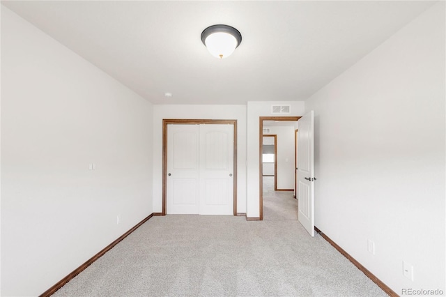 unfurnished bedroom with a closet, light carpet, and baseboards