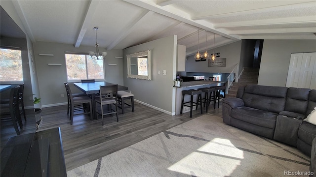 interior space with baseboards, lofted ceiling with beams, stairway, wood finished floors, and a notable chandelier