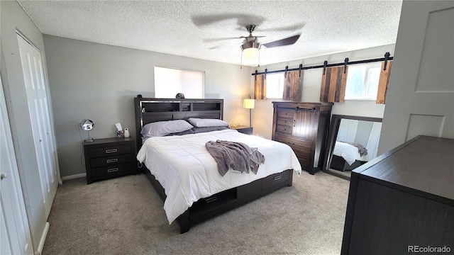 bedroom featuring light carpet, ceiling fan, a barn door, and a textured ceiling