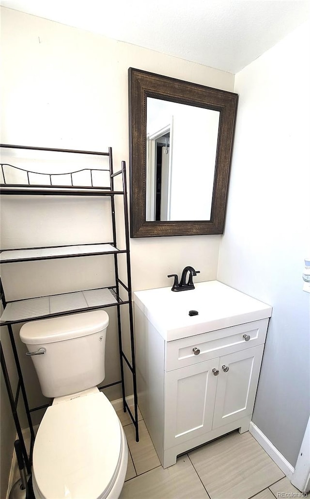 bathroom with baseboards, vanity, and toilet