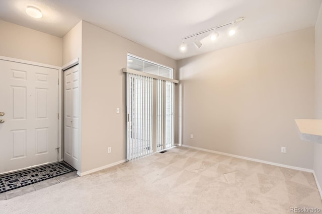 unfurnished room featuring track lighting and light colored carpet