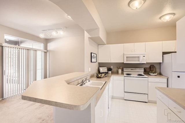 kitchen with sink, white appliances, kitchen peninsula, and white cabinets