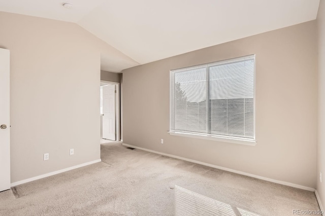 spare room featuring vaulted ceiling and light colored carpet