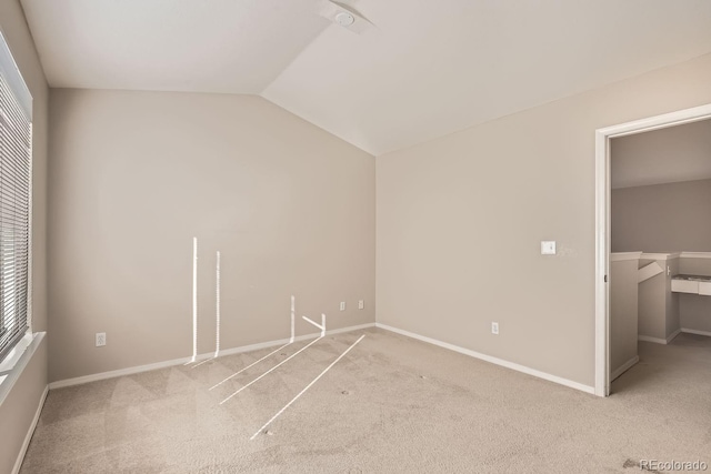 unfurnished bedroom with multiple windows, a spacious closet, vaulted ceiling, light colored carpet, and a closet