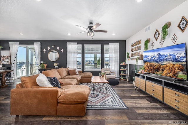 living room featuring ceiling fan, plenty of natural light, and dark hardwood / wood-style floors