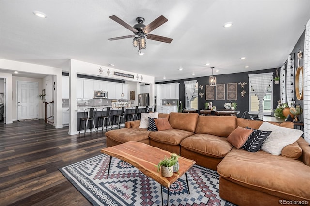 living room featuring ceiling fan and dark wood-type flooring