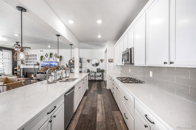 kitchen with white cabinetry, sink, dark wood-type flooring, stainless steel appliances, and decorative light fixtures