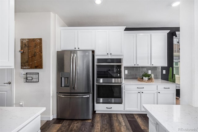 kitchen featuring decorative backsplash, white cabinets, appliances with stainless steel finishes, and dark hardwood / wood-style flooring