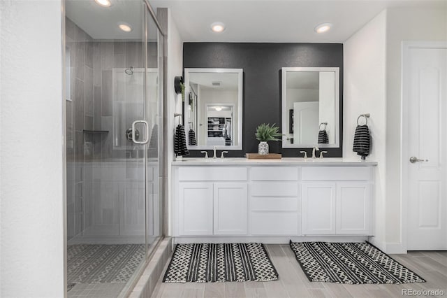 bathroom with wood-type flooring, vanity, and a shower with shower door