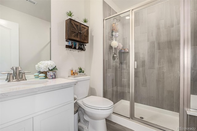 bathroom with wood-type flooring, vanity, toilet, and walk in shower