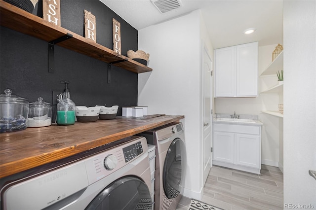 washroom with independent washer and dryer, sink, cabinets, and light hardwood / wood-style flooring