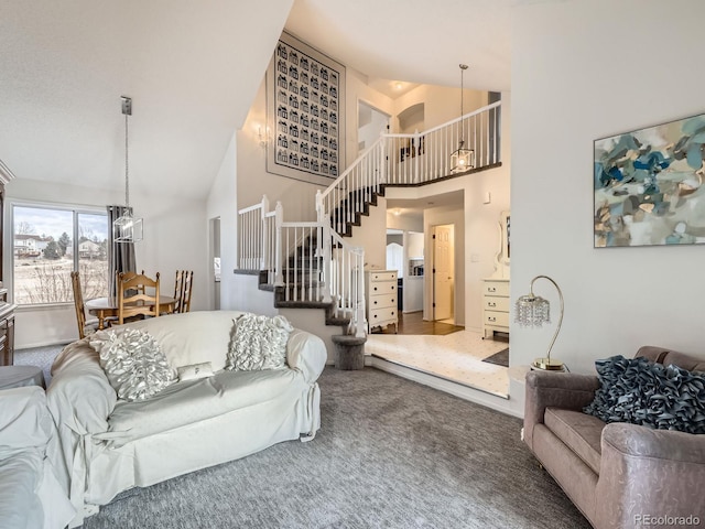 carpeted living room with high vaulted ceiling and a chandelier