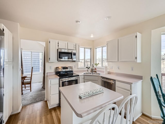 kitchen featuring white cabinetry, appliances with stainless steel finishes, sink, and a center island