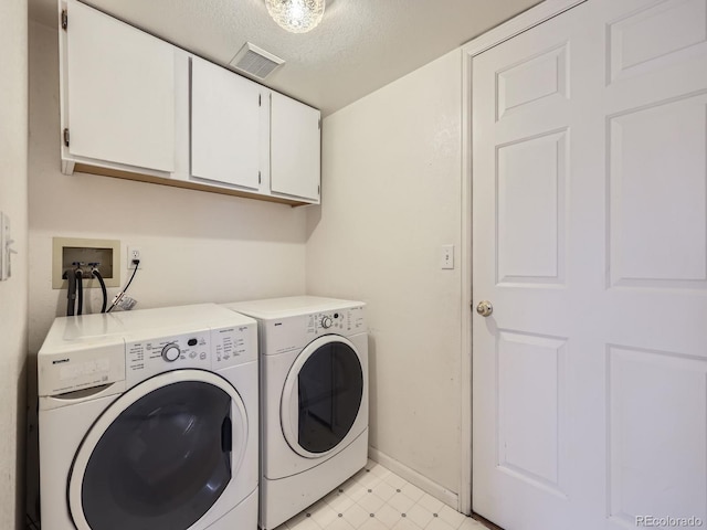 laundry area featuring independent washer and dryer, cabinets, and a textured ceiling