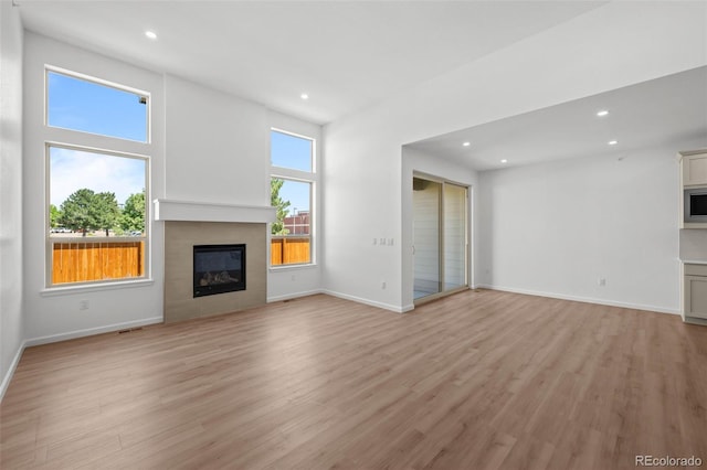 11341 W Alder Dr, Littleton, CO 80127 - unfurnished living room with light wood-type flooring, a glass covered fireplace, and recessed lighting