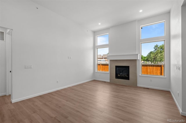 11341 W Alder Dr, Littleton, CO 80127 - unfurnished living room featuring light wood-style floors, a tile fireplace, and recessed lighting