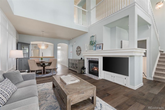 8318 Devinney Ct, Arvada, CO 80005 - living area with dark wood-type flooring, arched walkways, stairs, a brick fireplace, and a towering ceiling