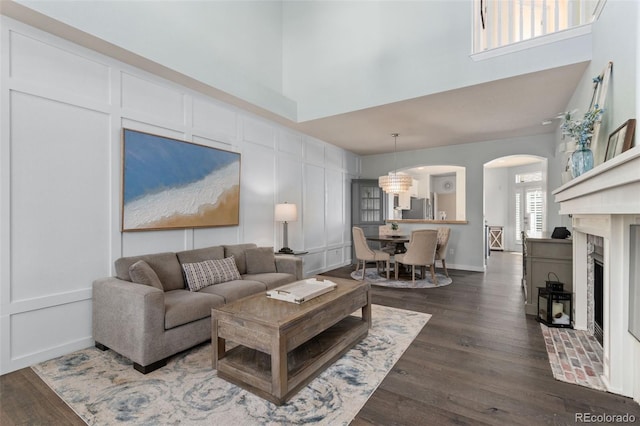 8318 Devinney Ct, Arvada, CO 80005 - living room with arched walkways, a high ceiling, dark wood-style floors, and a fireplace