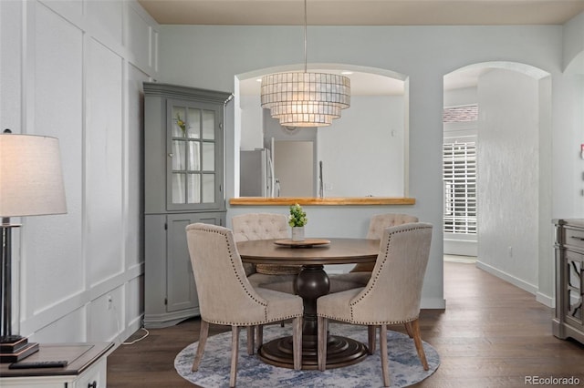 8318 Devinney Ct, Arvada, CO 80005 - dining space with dark wood finished floors, a chandelier, and arched walkways