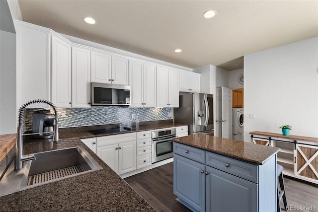 8318 Devinney Ct, Arvada, CO 80005 - kitchen with appliances with stainless steel finishes, washer / clothes dryer, dark wood-style floors, white cabinets, and decorative backsplash