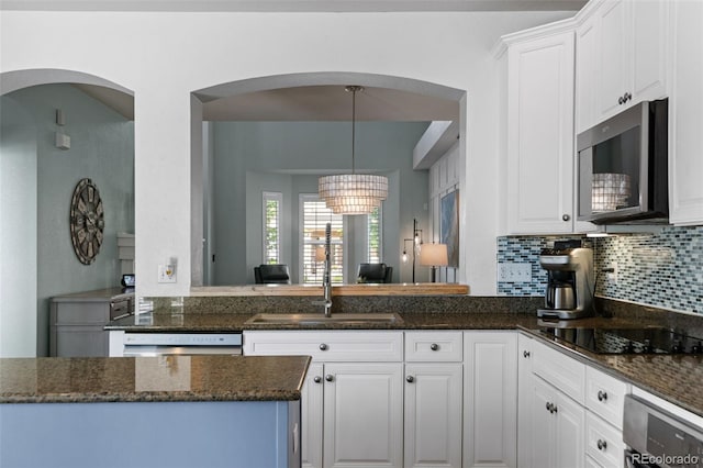 8318 Devinney Ct, Arvada, CO 80005 - kitchen with stainless steel microwave, black electric stovetop, white cabinets, and backsplash