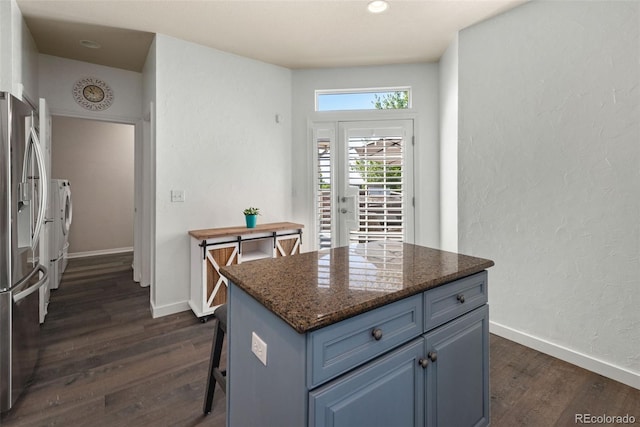 8318 Devinney Ct, Arvada, CO 80005 - kitchen featuring stainless steel fridge with ice dispenser, washing machine and clothes dryer, dark wood-type flooring, a center island, and blue cabinetry