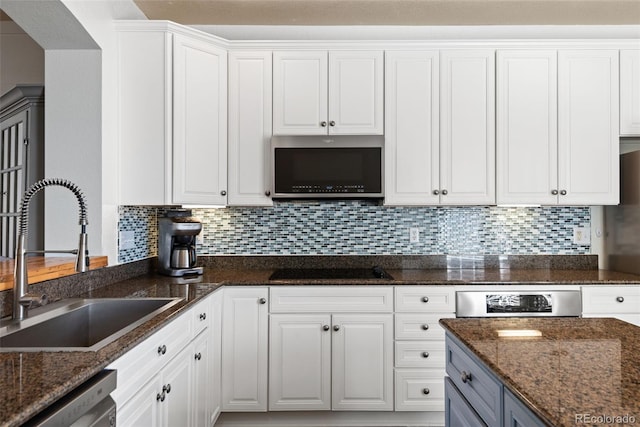 8318 Devinney Ct, Arvada, CO 80005 - kitchen with appliances with stainless steel finishes, white cabinetry, dark stone countertops, and decorative backsplash