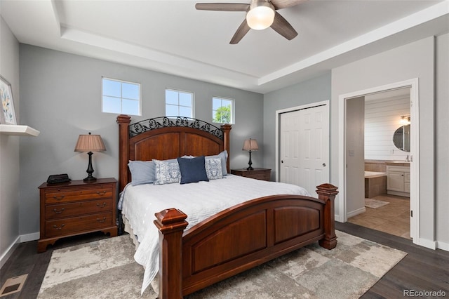8318 Devinney Ct, Arvada, CO 80005 - bedroom with dark wood-style flooring, a raised ceiling, connected bathroom, and a closet