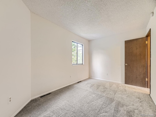 empty room with light carpet and a textured ceiling