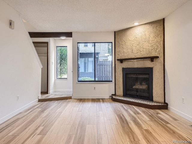 unfurnished living room featuring a textured ceiling, a fireplace, and light hardwood / wood-style floors