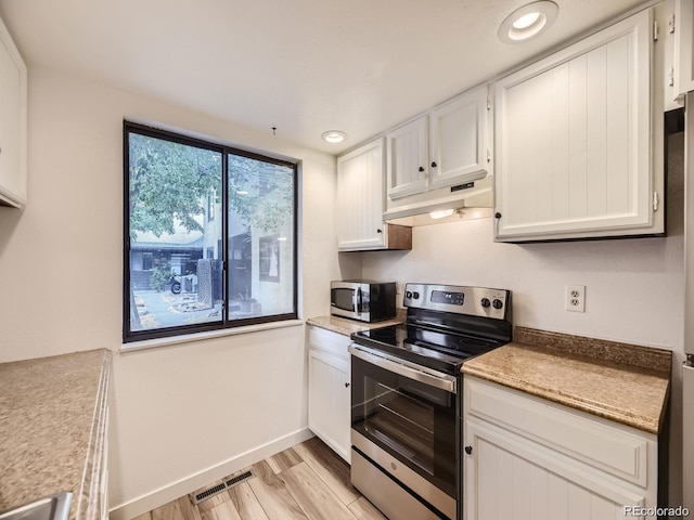 kitchen featuring stainless steel appliances, white cabinetry, light stone countertops, and light wood-type flooring