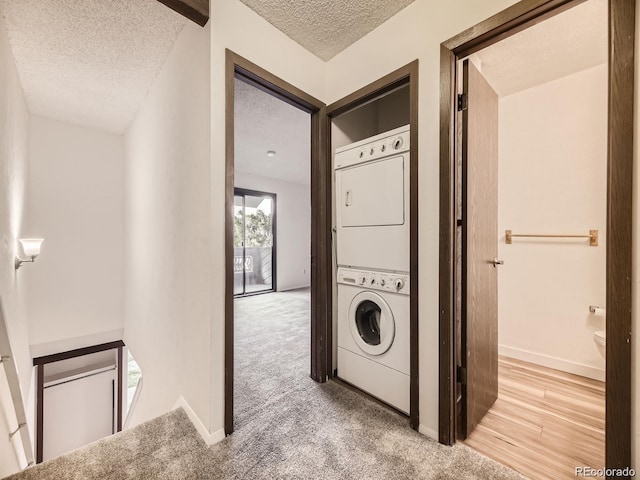 clothes washing area with stacked washer and dryer, carpet floors, and a textured ceiling