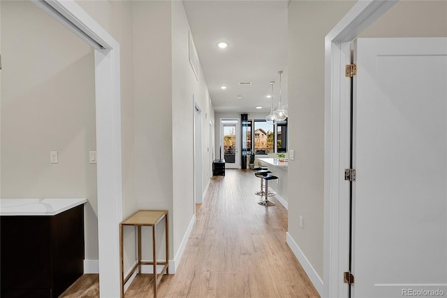 corridor with light wood-type flooring, recessed lighting, and baseboards