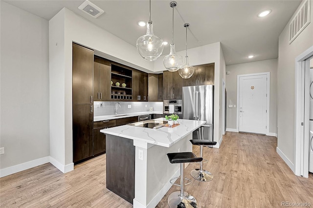 kitchen featuring dark brown cabinetry, visible vents, appliances with stainless steel finishes, open shelves, and a sink