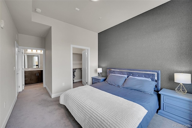 carpeted bedroom with baseboards, a walk in closet, and ensuite bath